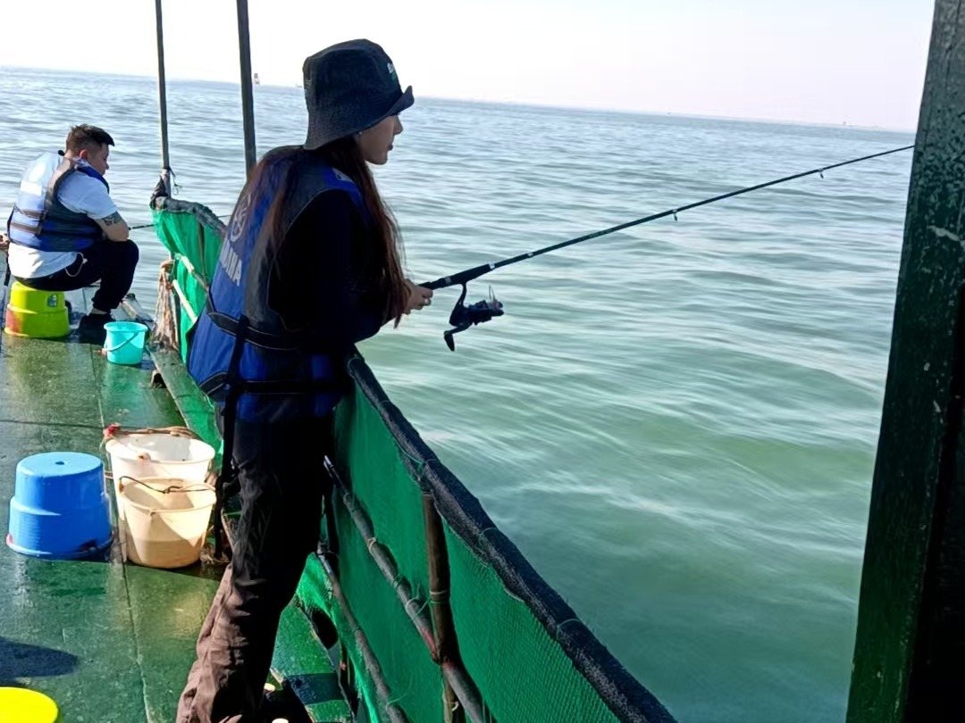 游客在北海木船上使用钓竿近海垂钓